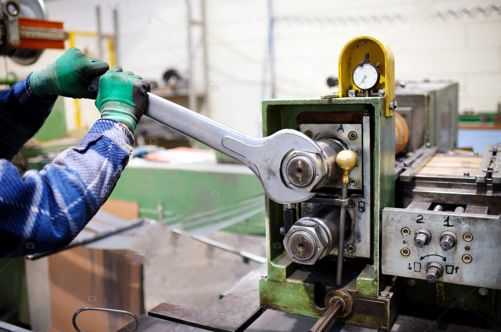 Worker adjusting machinery with large metal wrench